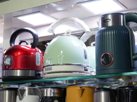 An electric kettle and toaster set out on a glass shelf.