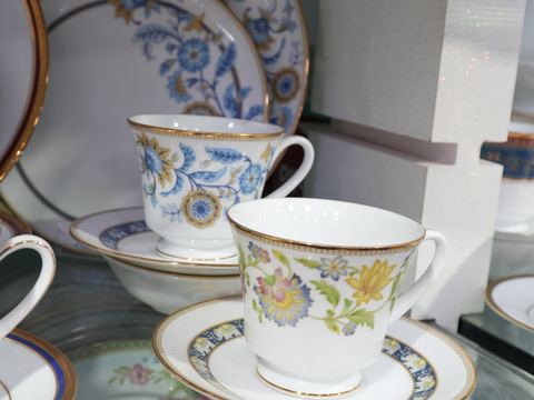 A bone china teacup and saucer with a floral gold-rimmed pattern.