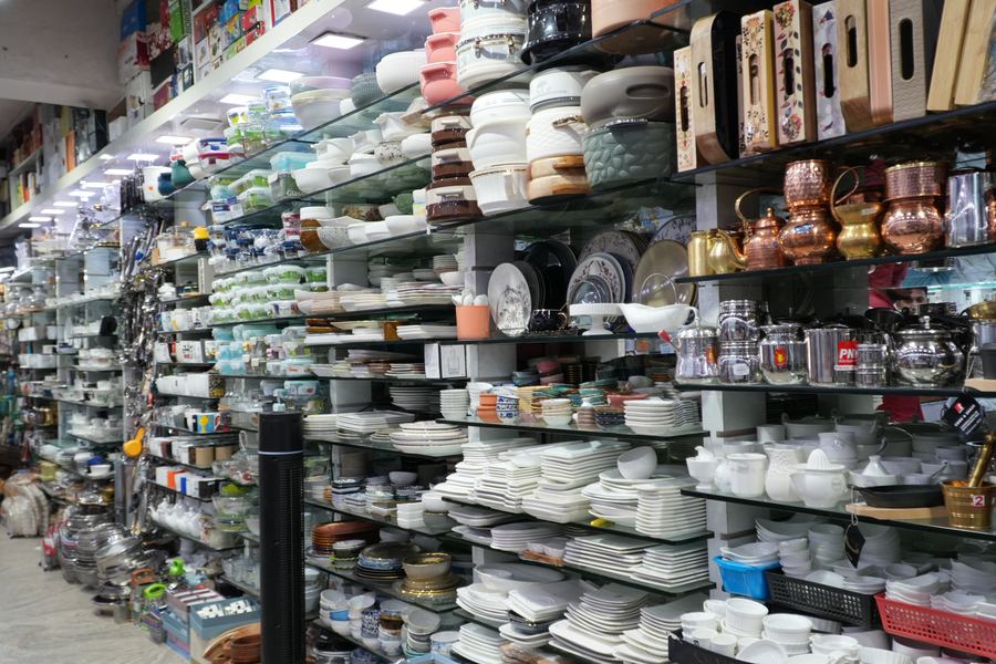 Shelves inside the shop stacked with crockery, glassware, storage jars and copper vessels.