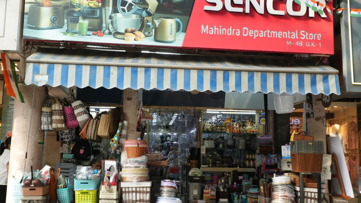 The shopfront of Mahindra Departmental Store at M-48, M Block Market, Greater Kailash-1, under its blue and white striped awning.